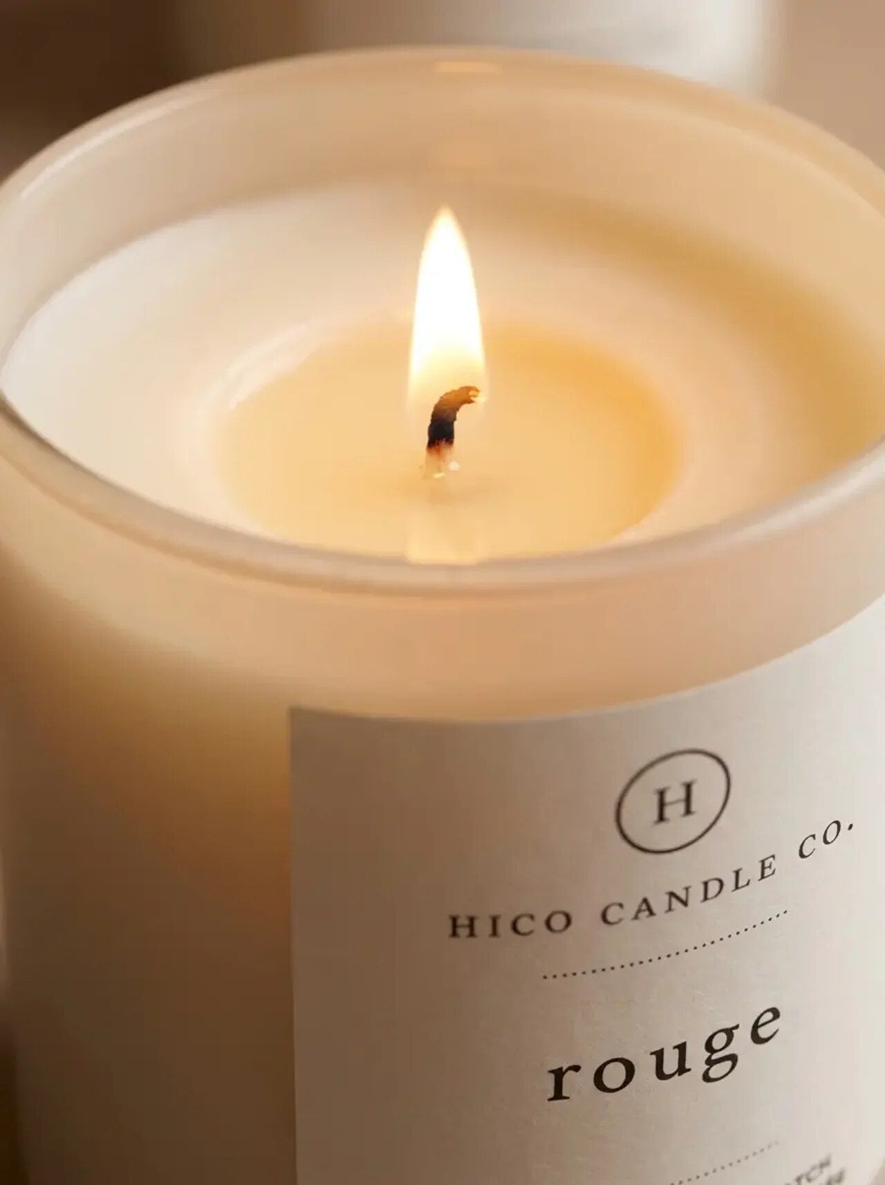 Close view of the Hico Rouge candle flame and label.