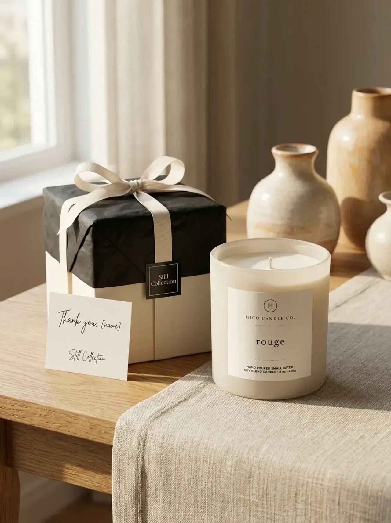 Hico Rouge candle with a ribbon-tied gift box and a small vase.
