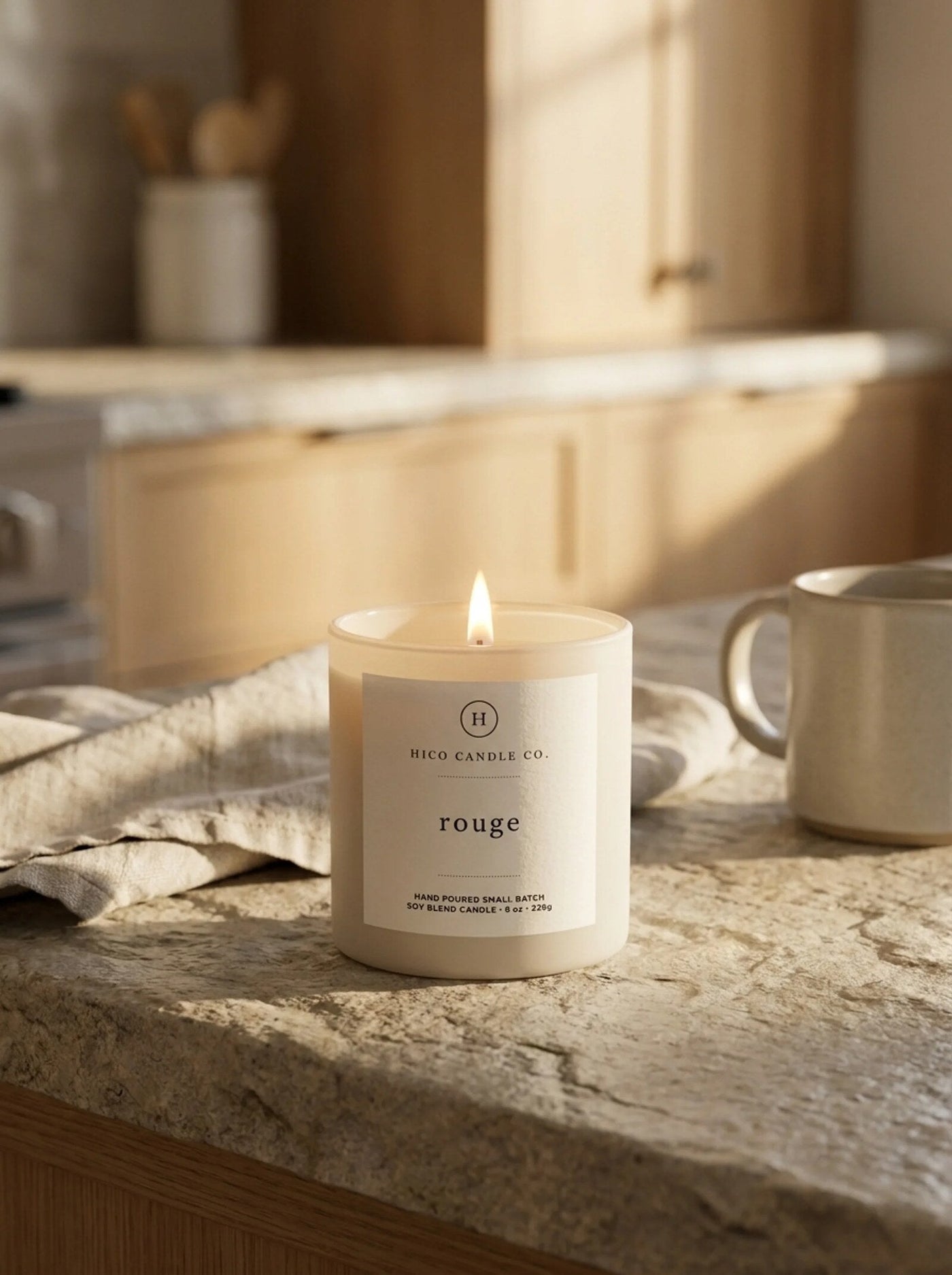 Hico Rouge candle on a marble counter beside a coffee mug.